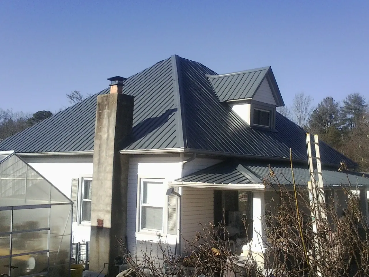 Dark blue standing seam metal roof on a white farmhouse with dormer — Slate & Tile Roof Repair by Roofing Brothers in Hegins