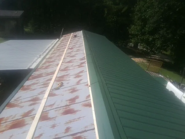 Old rusted panels beside newly installed green metal roofing — Wind Damage Roof Repair by Roofing Brothers in Hegins
