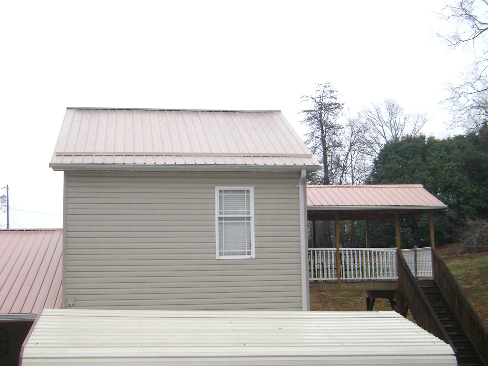 Tan metal roofs on a two story addition and attached porch, from a Roof Replacement job in Hegins