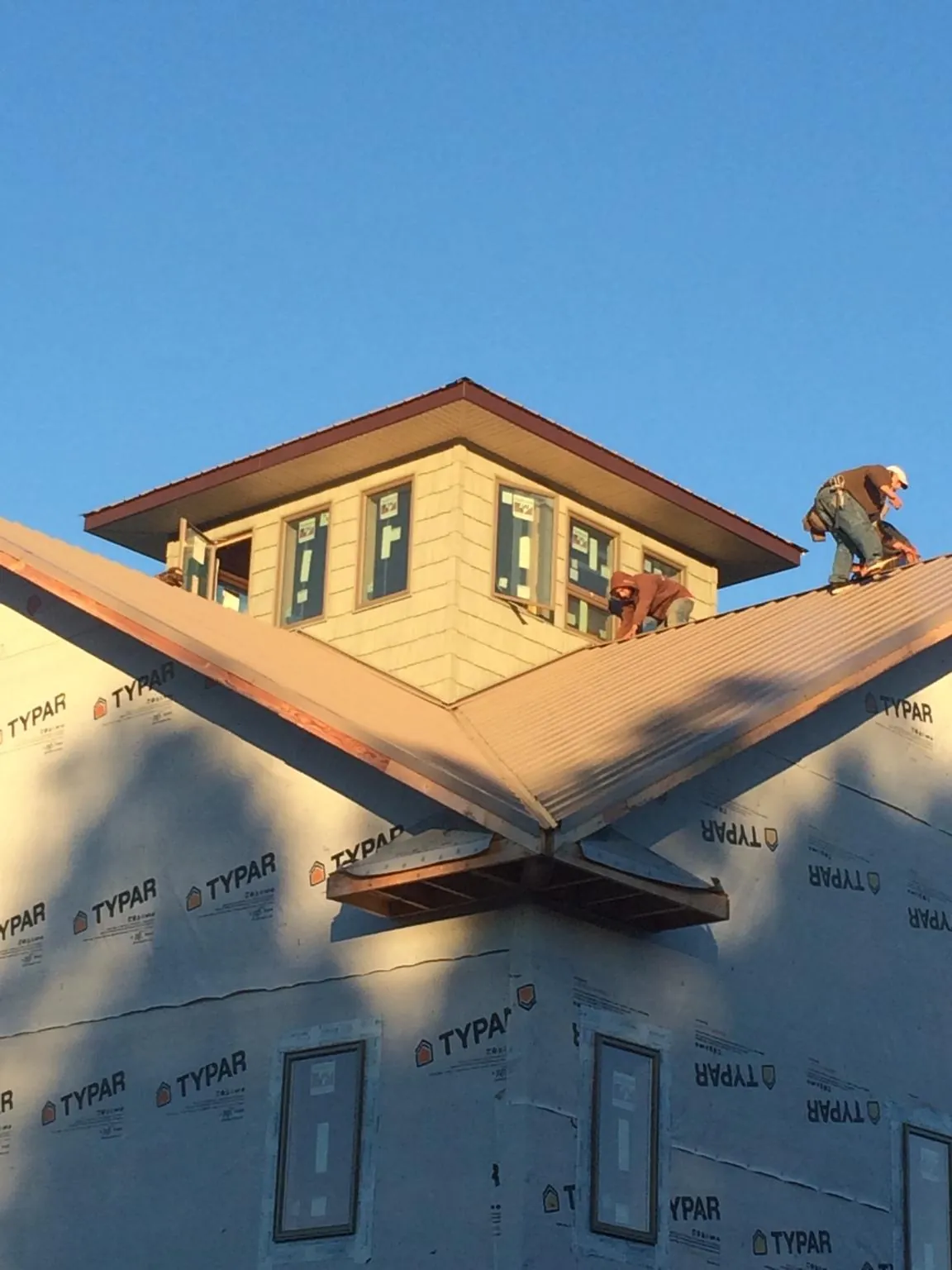 Roofers working around a rooftop cupola on a new metal roof at sunset — Roof Waterproofing in Hegins by Roofing Brothers